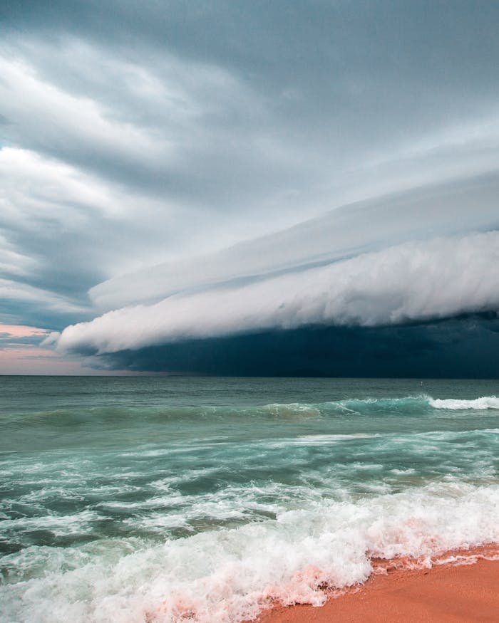 Thunderous storm clouds gather over the ocean, creating a dramatic seascape with rolling waves.