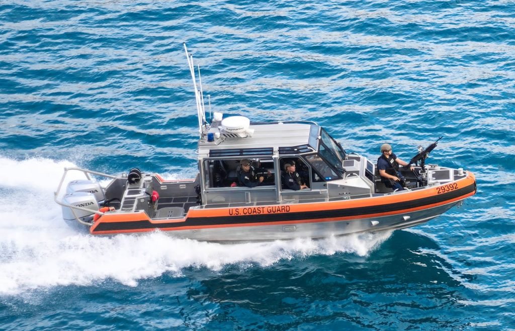 Dynamic U.S. Coast Guard patrol boat speeding through blue ocean waters, showcasing security and marine operations.